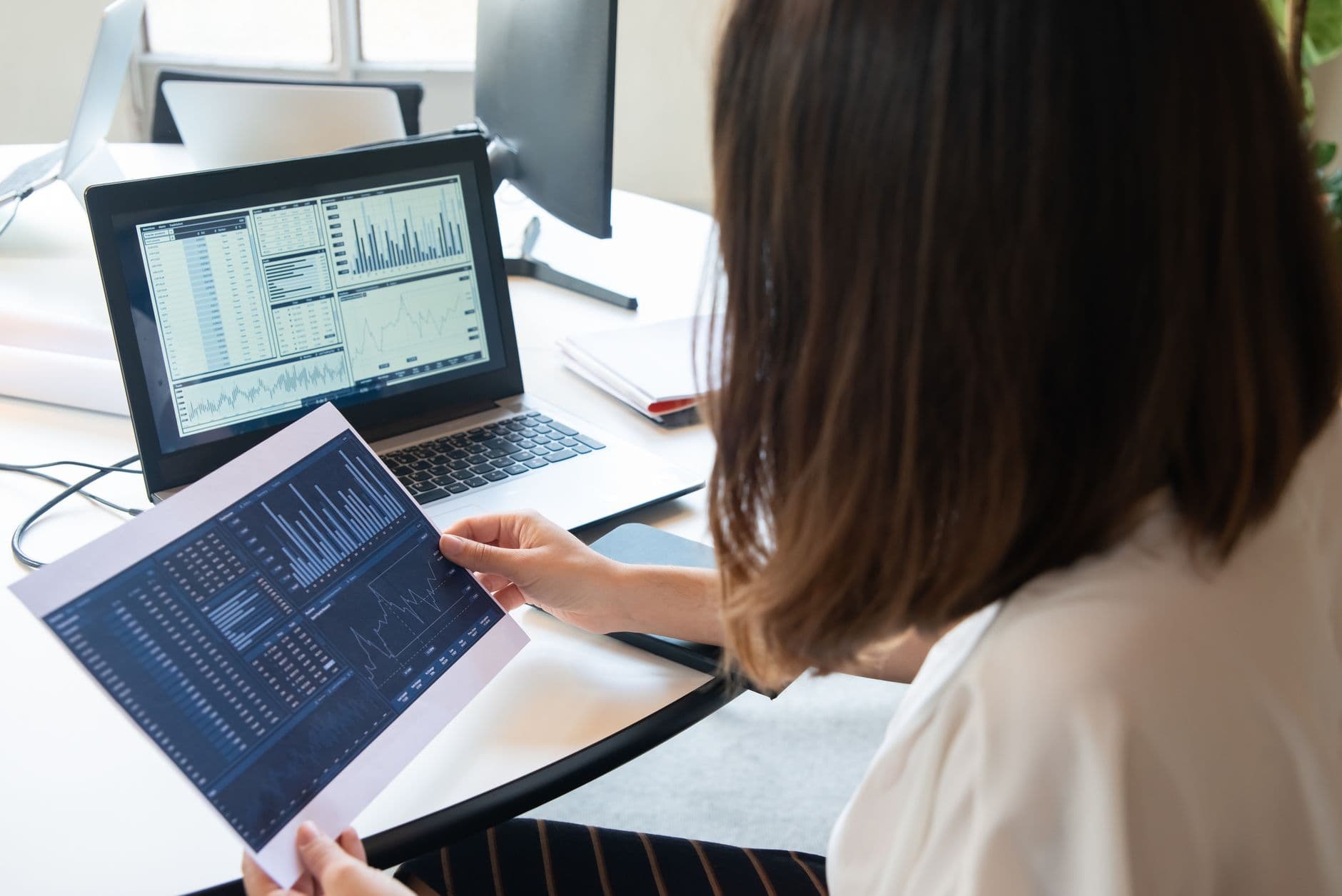 Pequeno comerciante conferindo uma nota fiscal em um computador no balcão.