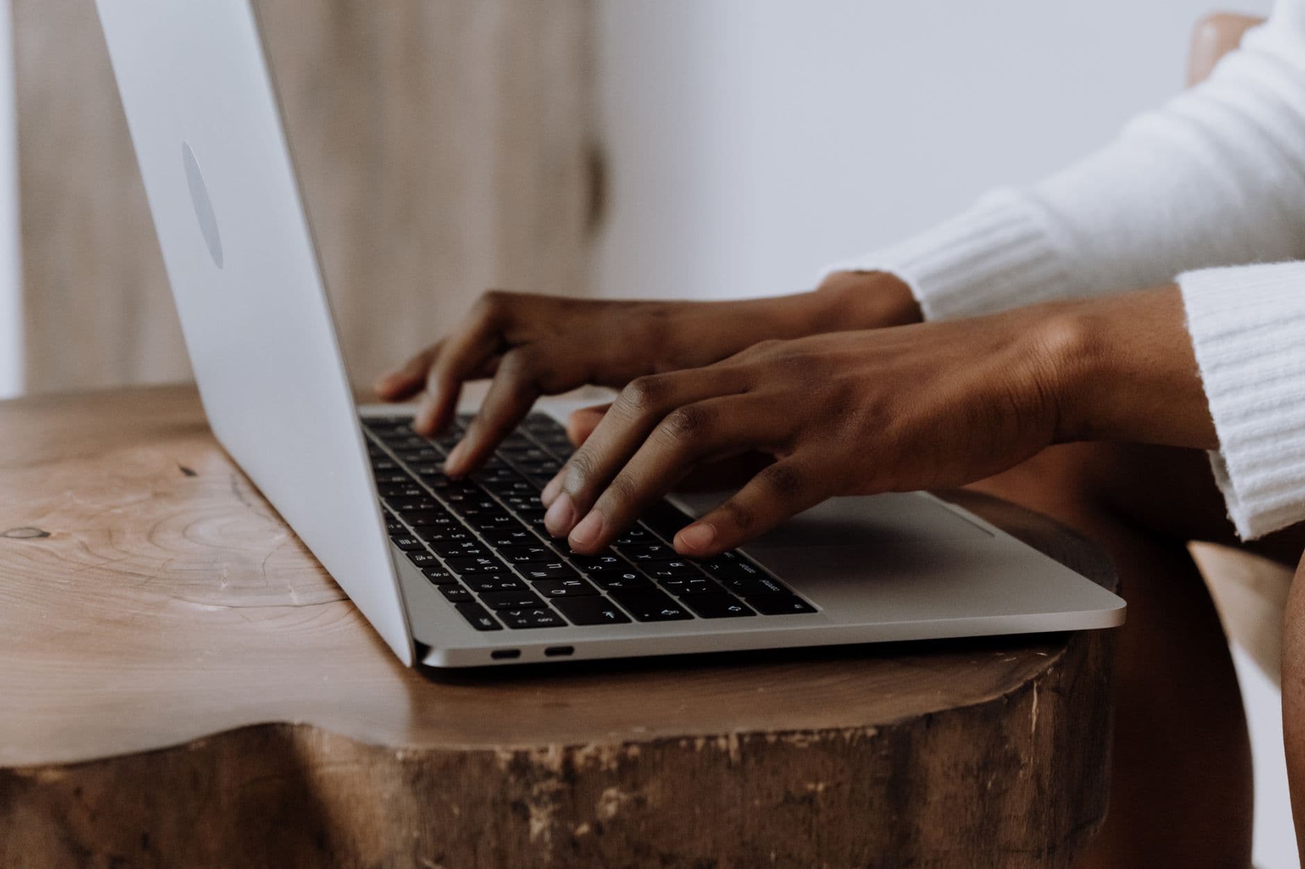 Hands typing on a laptop in a cozy indoor setting, focusing on technology and digital work.