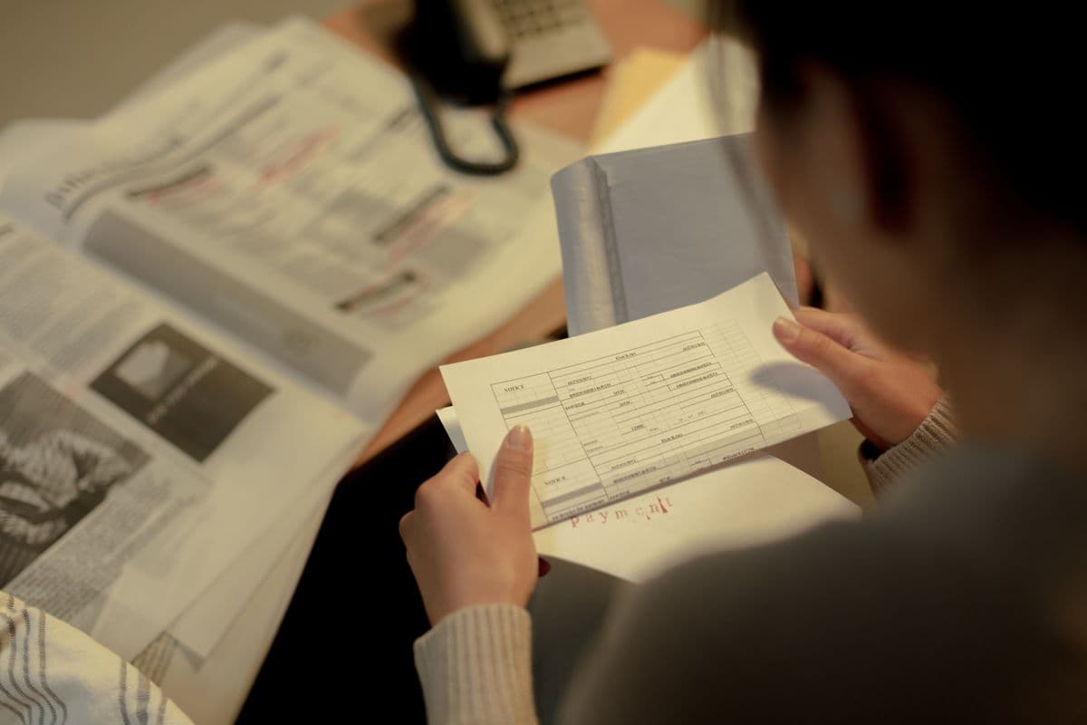 Prestadora de serviço conferindo dados de uma nota fiscal em uma mesa de trabalho.