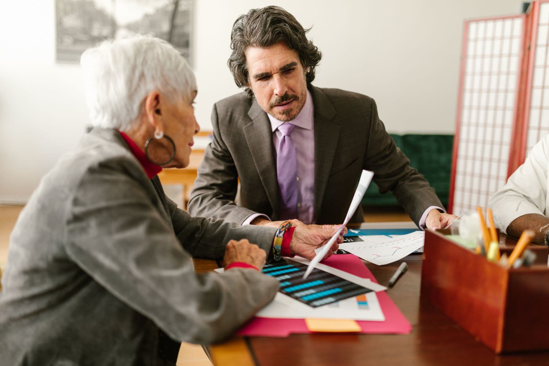 Elderly business professionals discussing reports in a modern office setting.