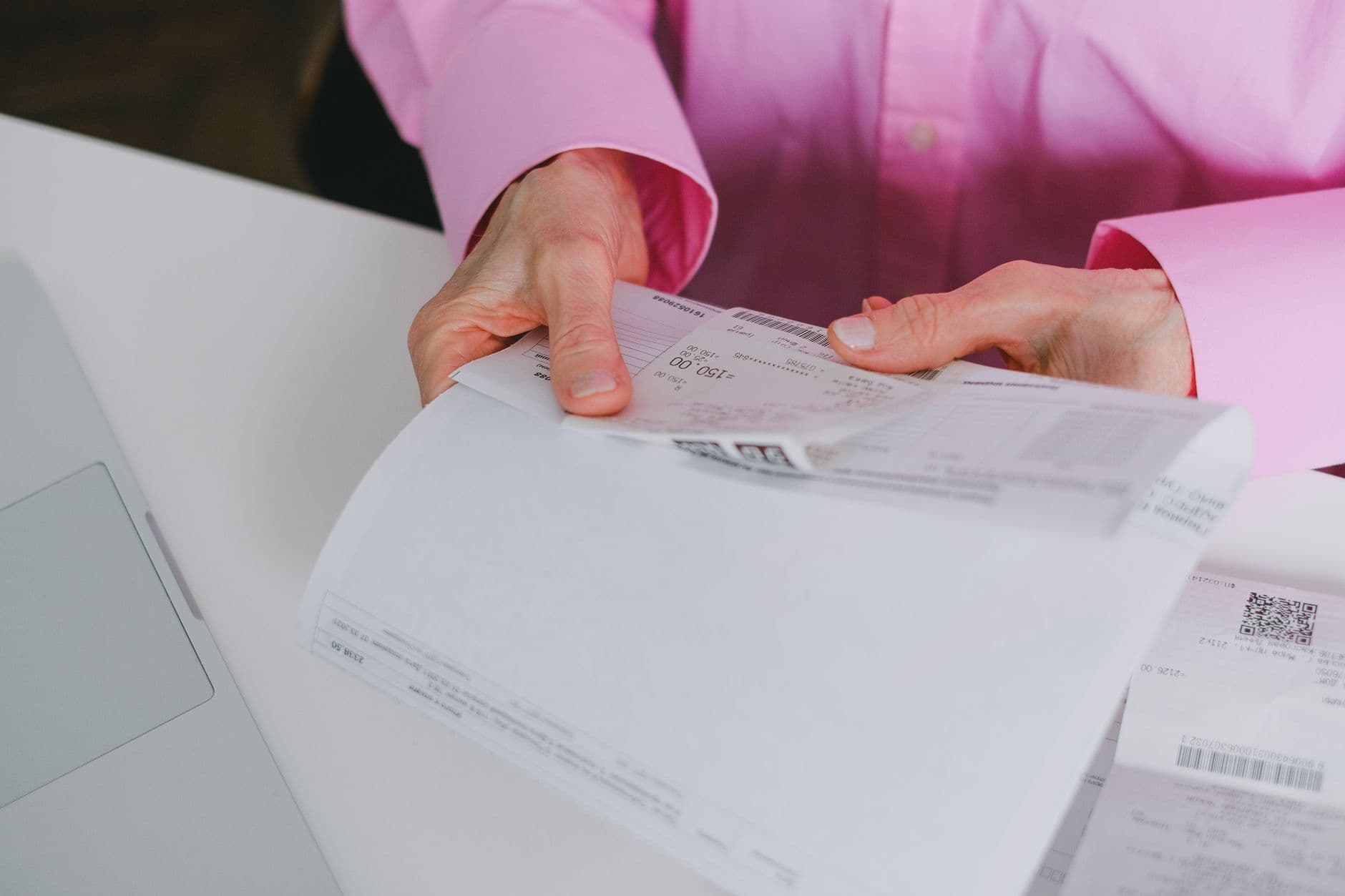 Pequeno empresário conferindo uma nota fiscal recusada ao lado do computador.