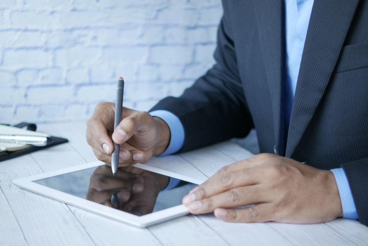 Custo e como decidir Homem de terno assinando documento digital em um tablet