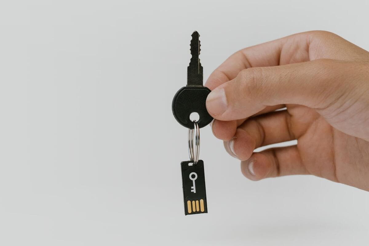 Mão segurando uma chave com um pen drive de segurança