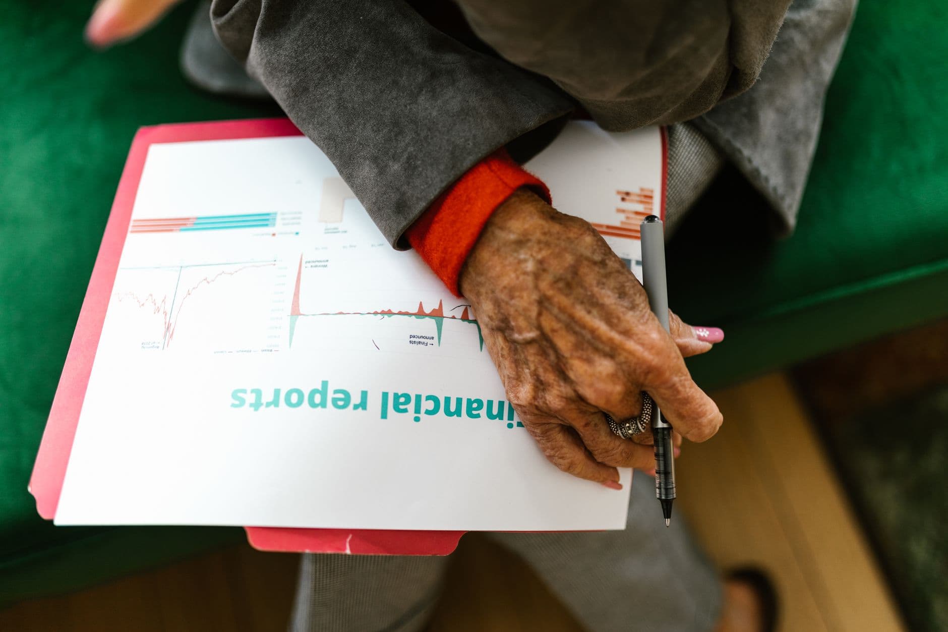 Como controlar notas emitidas em uma planilha simples Close-up of an elderly woman holding a pen with a financial report.