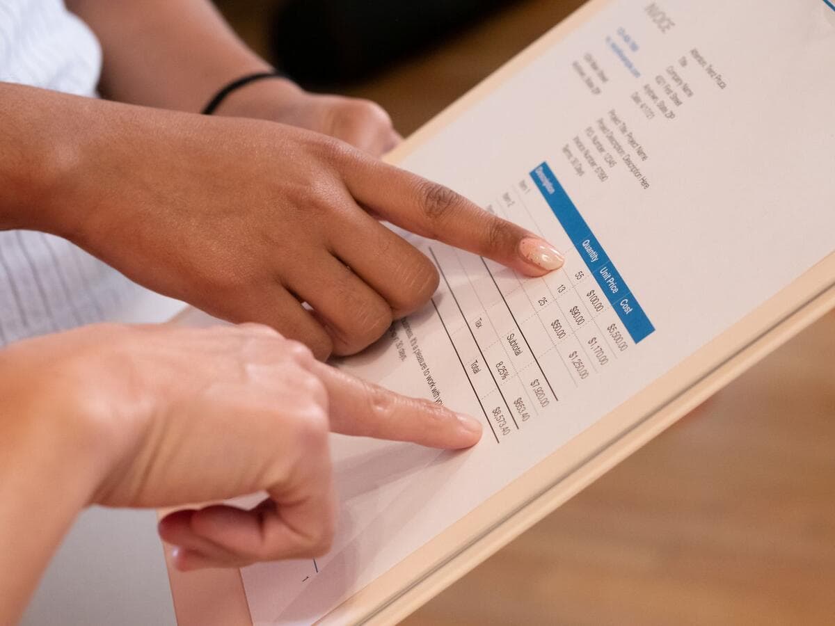 Compras de empresas do Simples Nacional e transição Duas pessoas apontando para valores em um documento financeiro