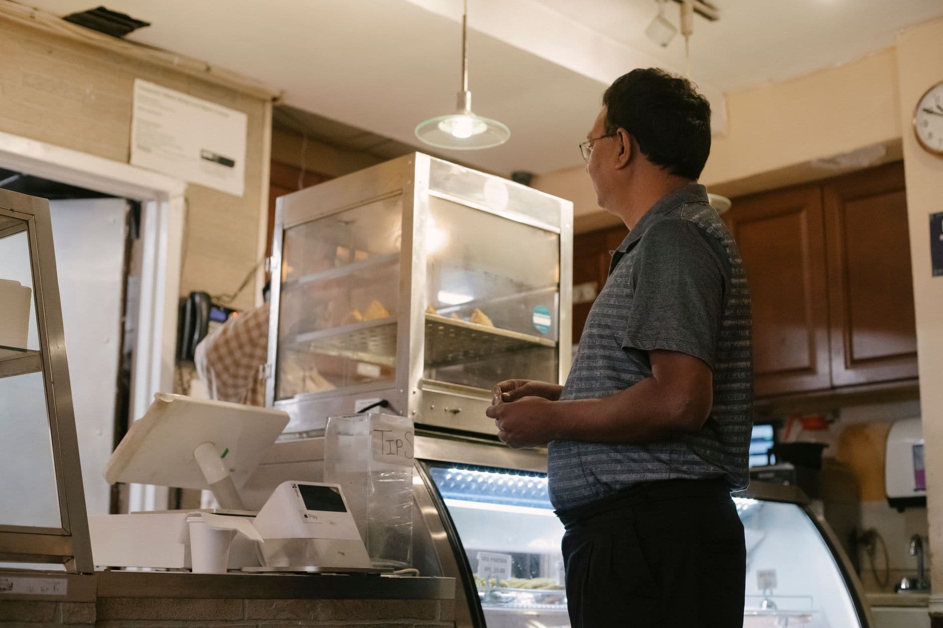 SAT e cupom fiscal eletrônico em São Paulo: o que existe Side view of ethnic male wearing casual clothes standing near showcase and cash register while buying food in grocery store