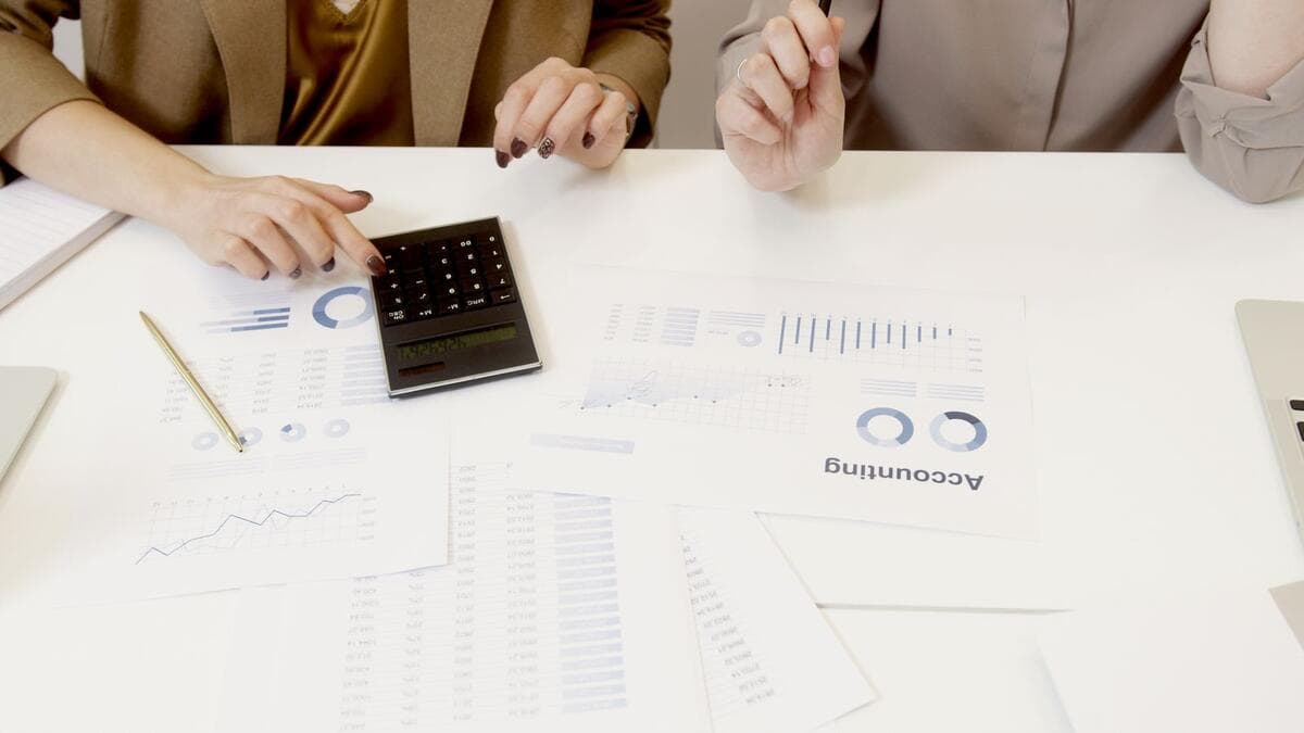 Limites para emitir com competência anterior Dois profissionais analisando documentos financeiros com calculadora
