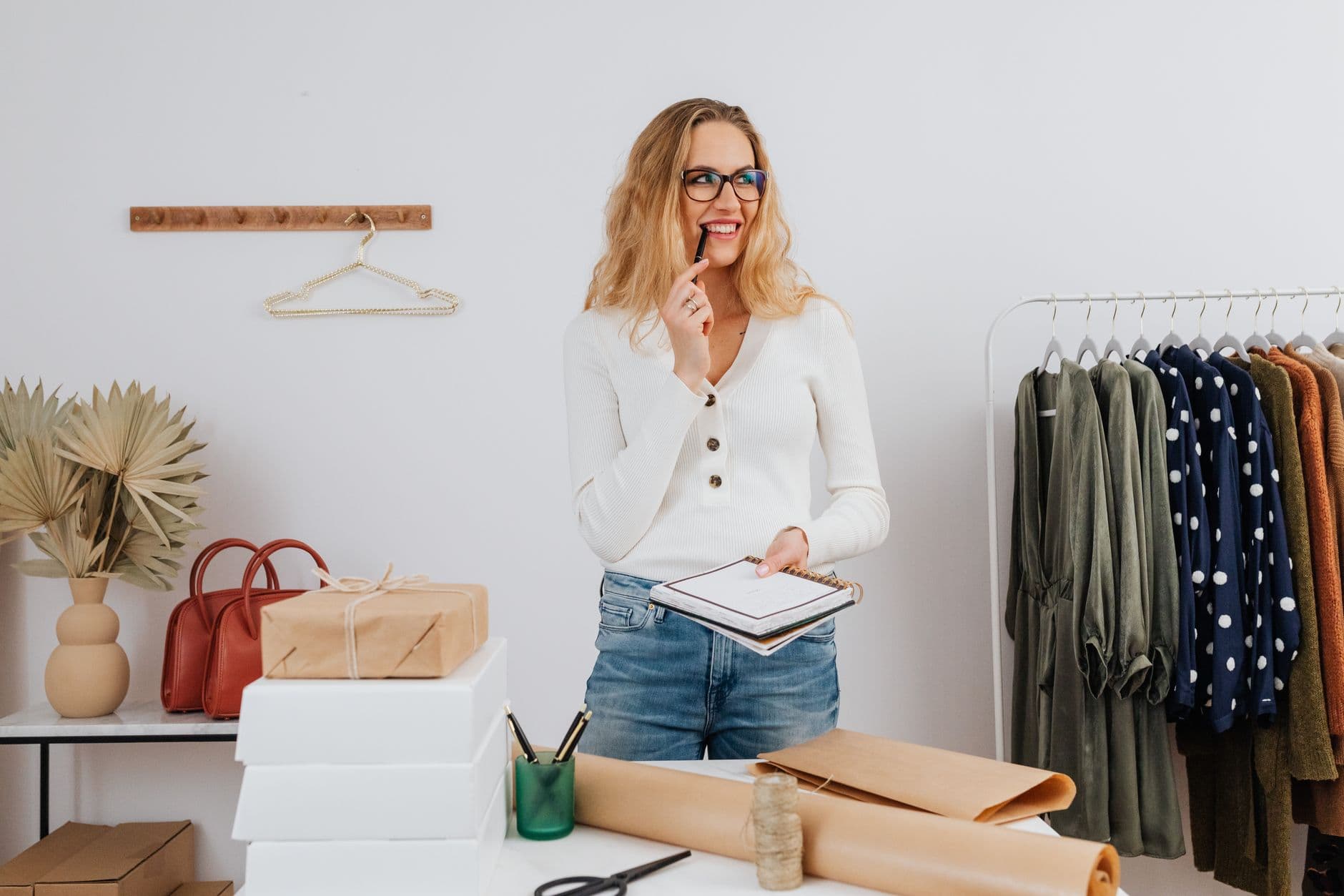 MEI precisa de certificado digital para emitir nota? Woman smiling while planning inventory at a boutique shop, wearing casual attire.