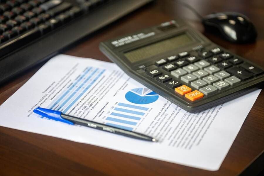 Documentos e calculadora sobre a mesa para controlar cobranças Documentos e calculadora sobre a mesa para controlar cobranças