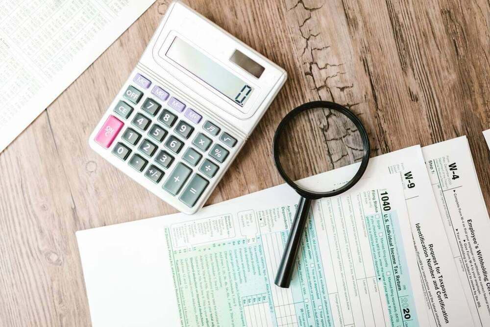 Formulários de imposto com calculadora e lupa sobre a mesa