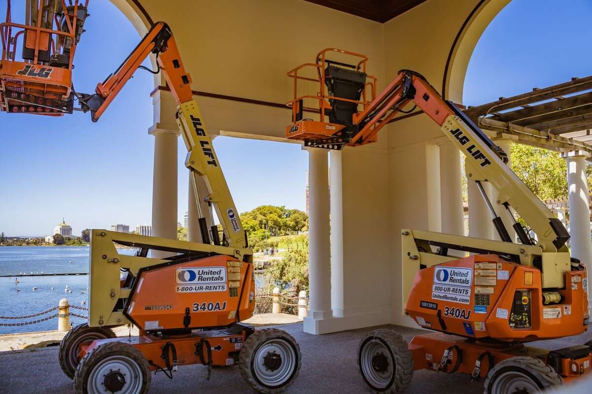 Plataformas elevatórias laranja estacionadas em uma área aberta