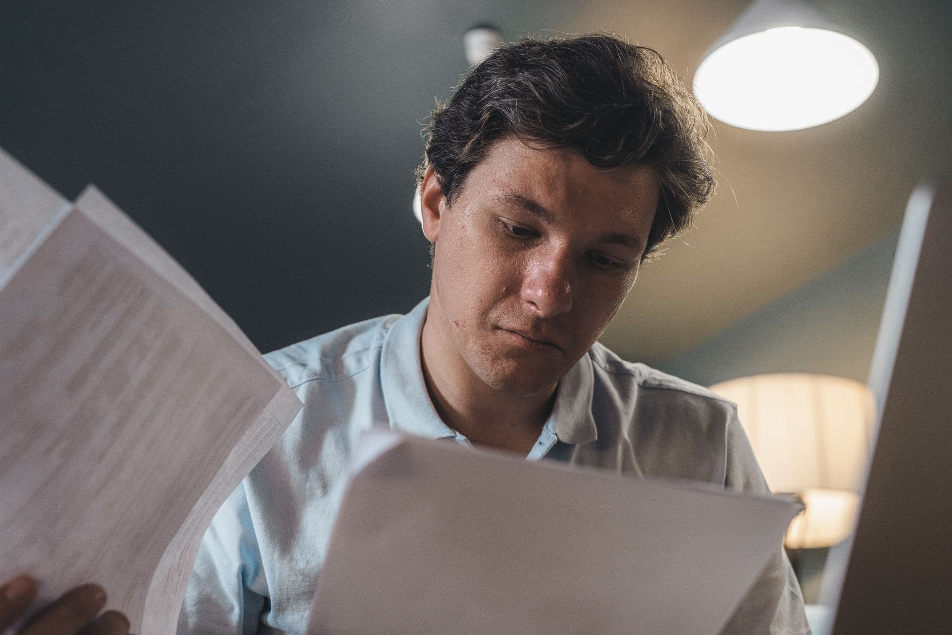 Microempreendedora conferindo uma nota fiscal com documentos sobre o balcão.
