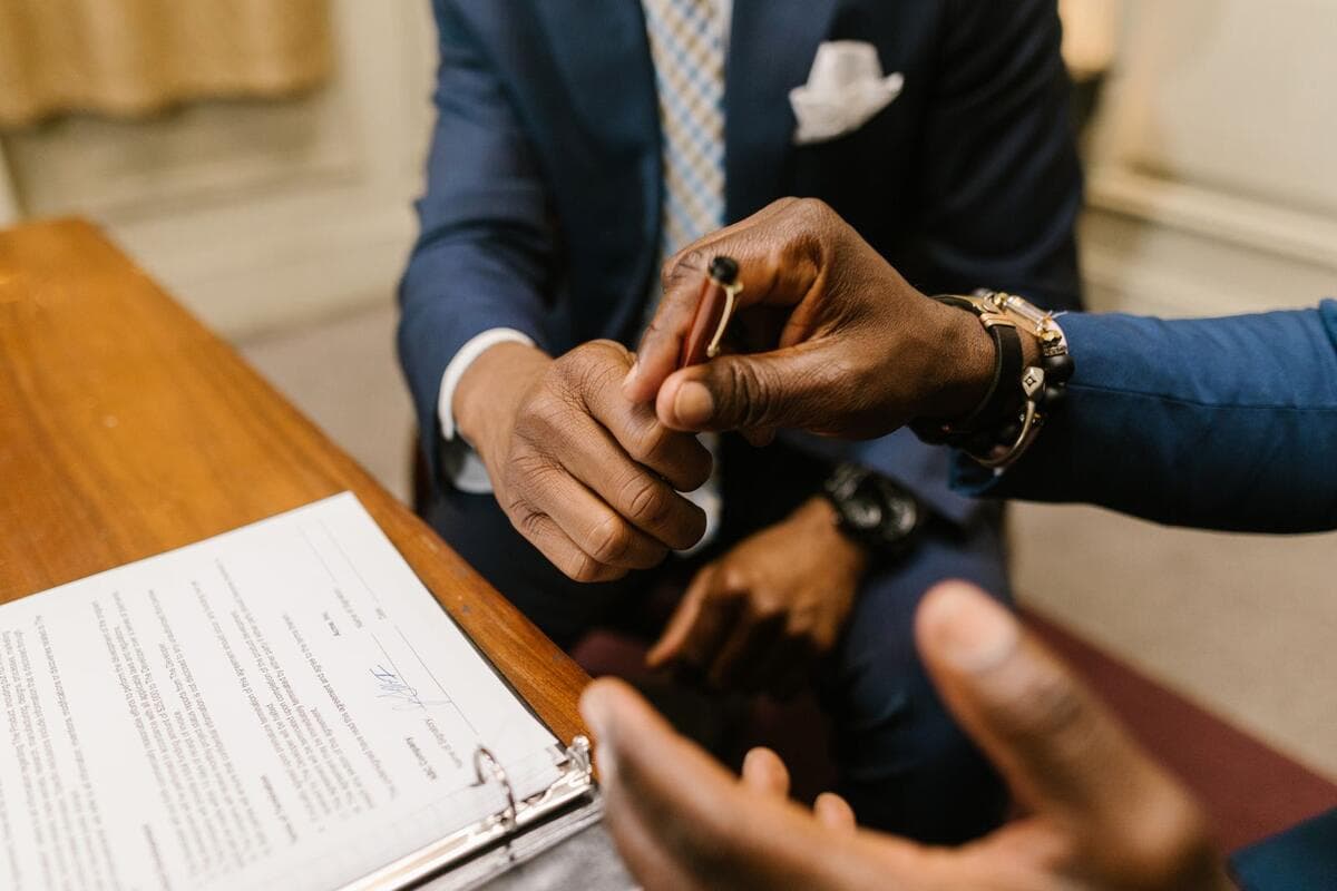 O risco do emprego disfarçado e como formalizar Mãos assinando um contrato de prestação de serviço sobre a mesa