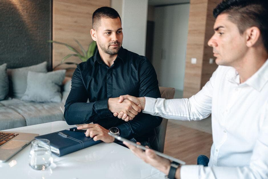 Dois homens apertando as mãos sobre uma mesa de escritório