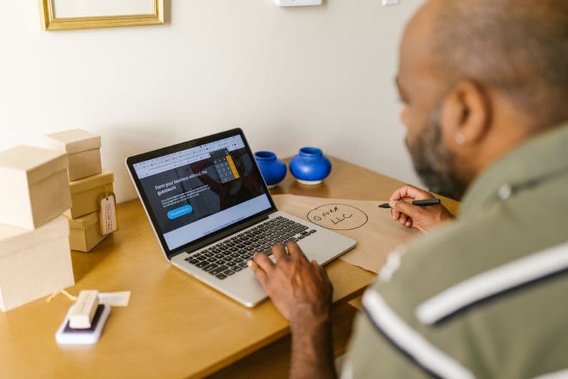 MEI trabalhando para uma empresa só: riscos e cuidados Entrepreneur at a desk using a laptop for business planning. Ideal for tech and startup themes.
