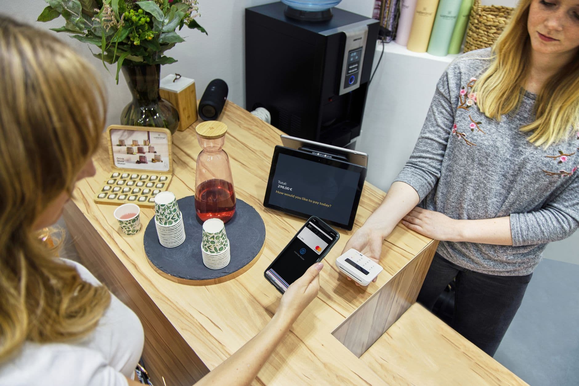 NFC-e: o que é e quando usar no lugar da NF-e A woman makes a contactless payment at a stylish Berlin café, emphasizing technology and modern retail.