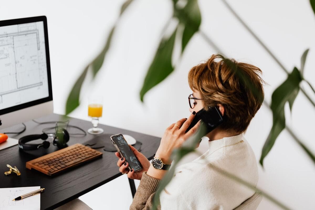 Retenções, cliente e como evitar o erro Mulher falando ao telefone enquanto trabalha no computador