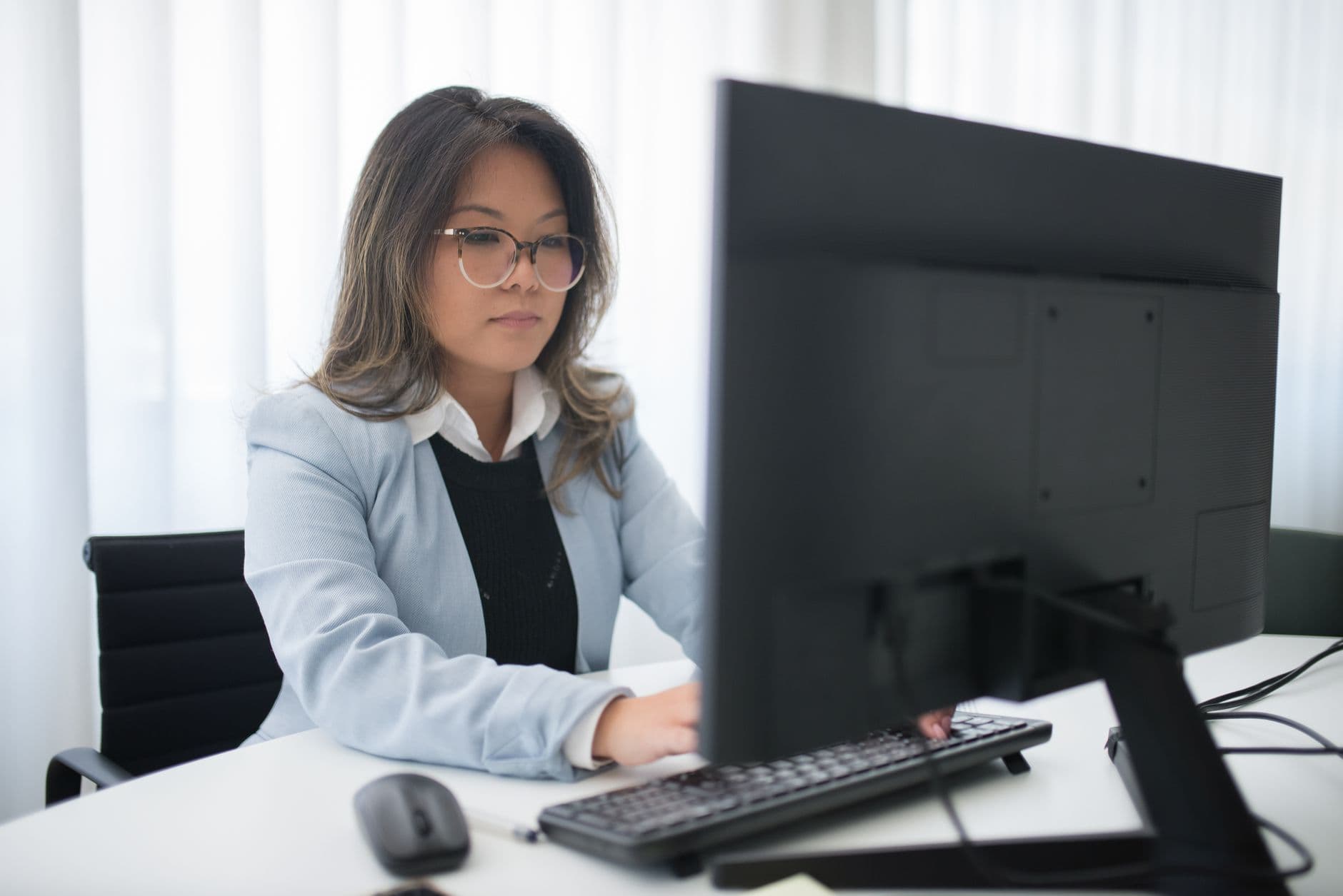 Como emitir NFS-e em Nova Odessa Confident businesswoman focused on work at desk with computer in modern office.