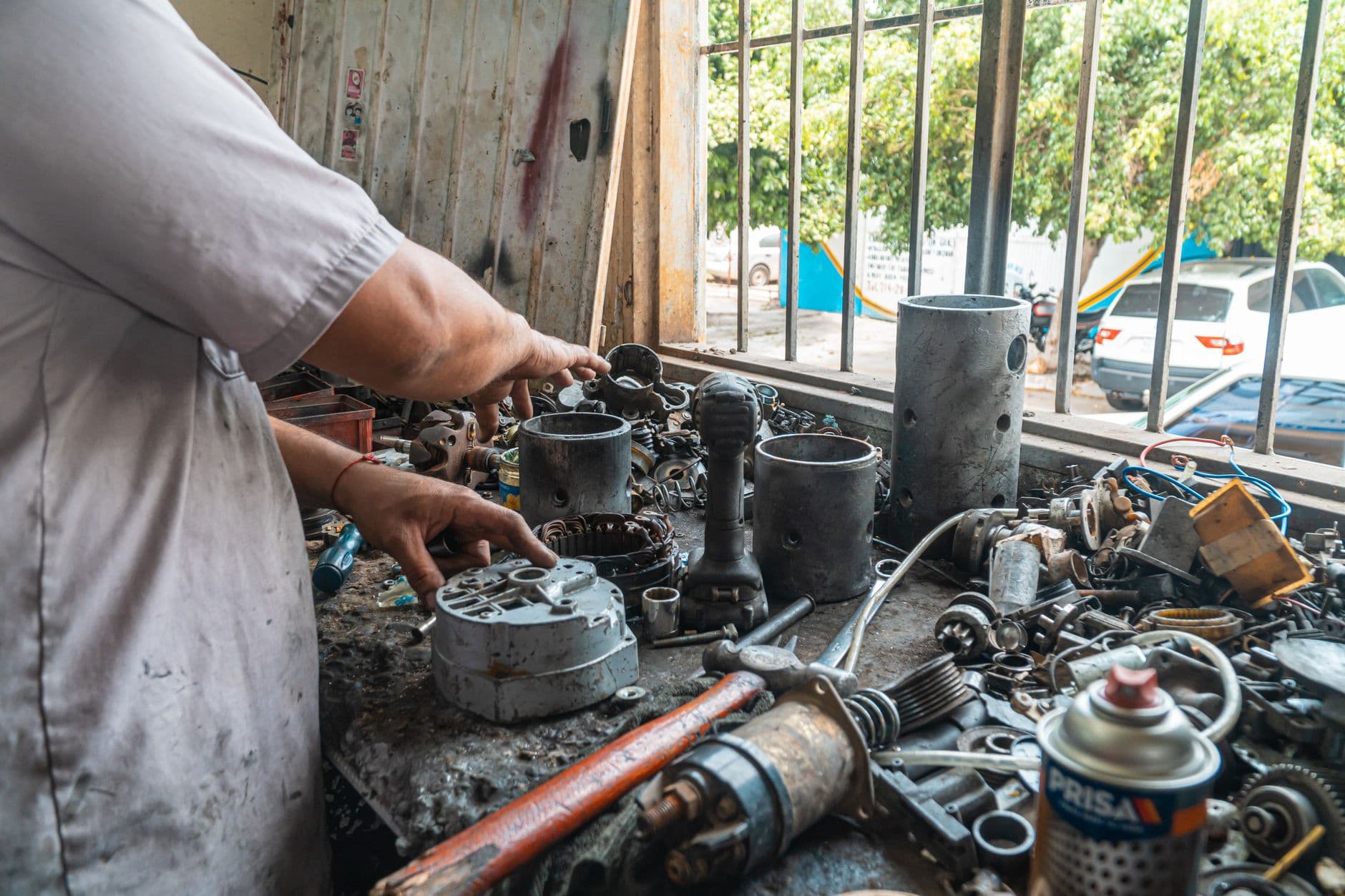 Nota de remessa: quando emitir e como preencher Mechanic arranging car parts on a cluttered work table in an automotive workshop.