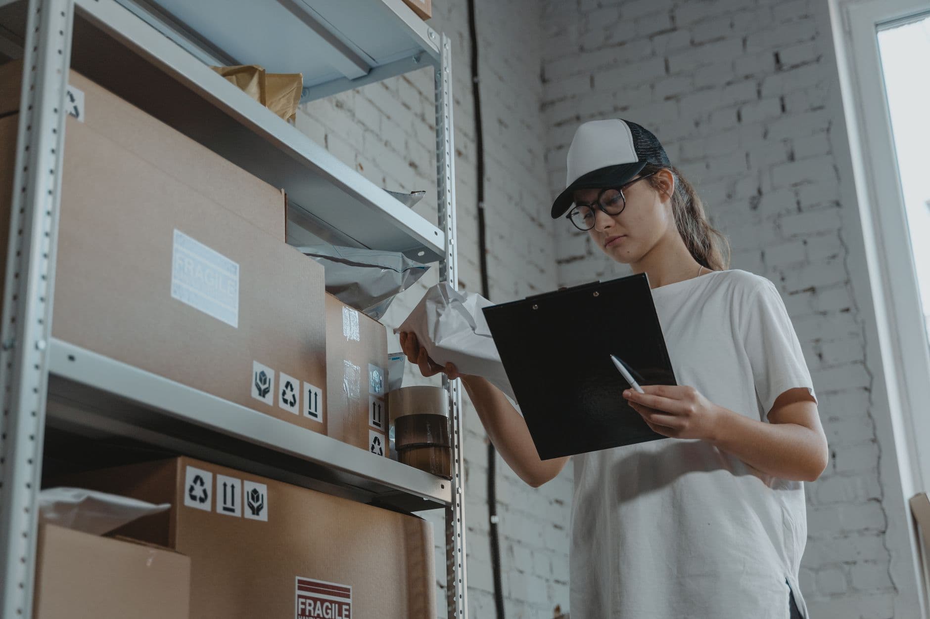 CT-e e MDF-e: documentos do transporte de cargas Warehouse worker organizing packages on shelf with clipboard.