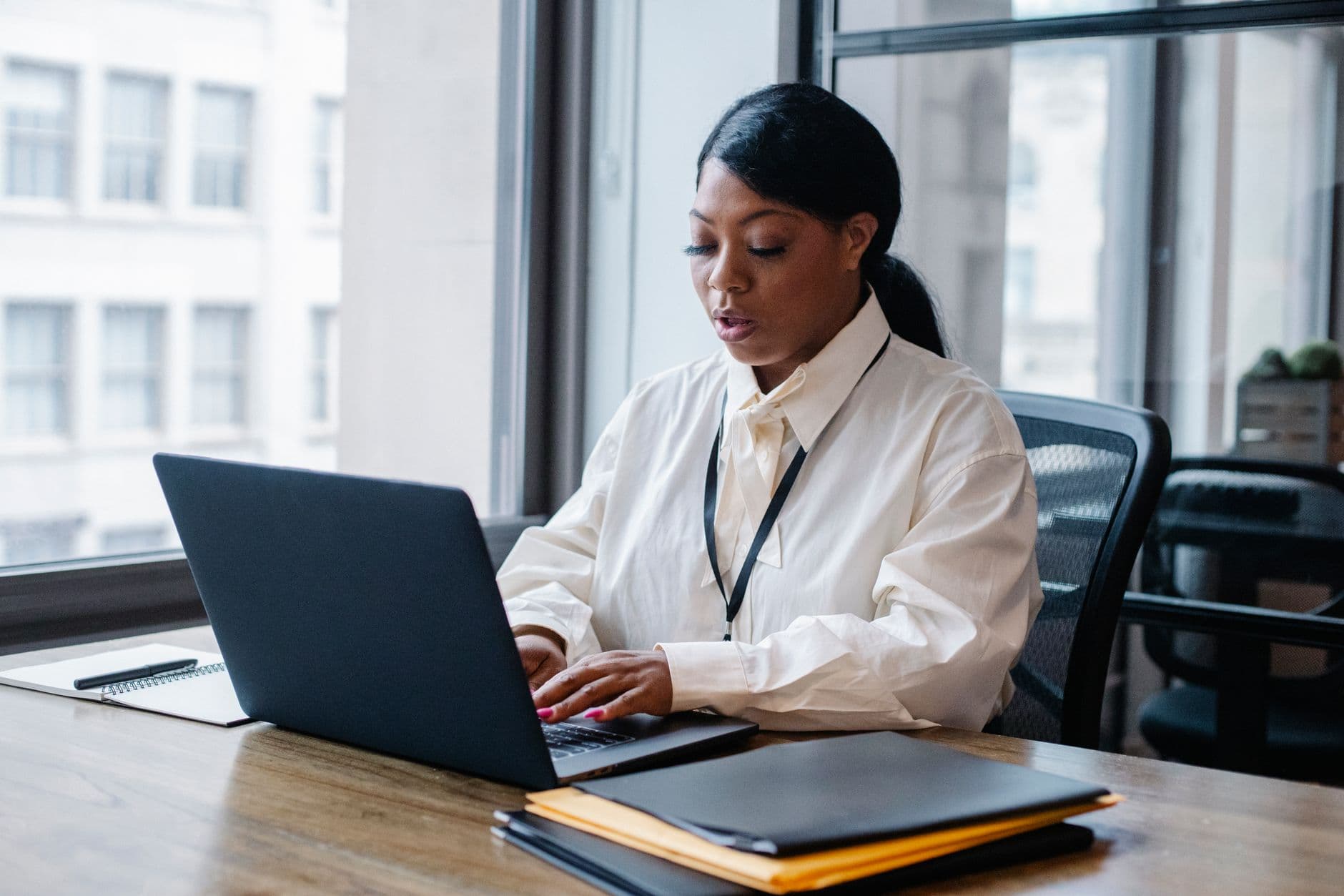 Como preencher a nota fiscal do MEI sem errar Concentrated African American female manager in white shirt working on computer during working process