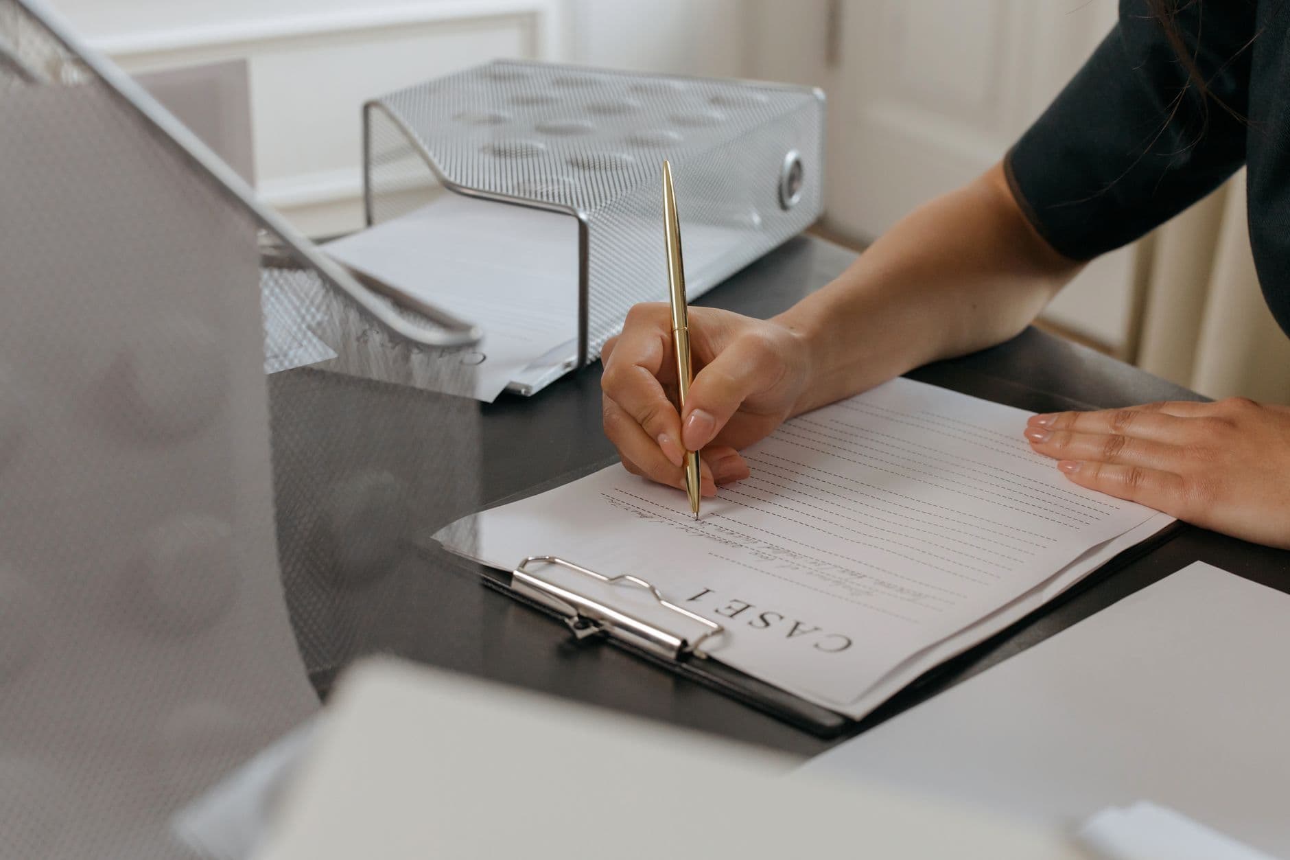 Cliente devolveu o produto: o que o MEI deve emitir Close-up of a woman writing on documents with a gold pen in an office environment.