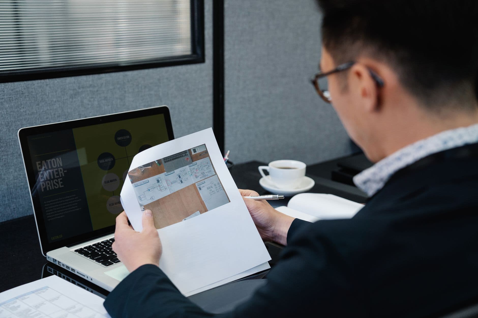 MEI vendendo para outro estado: o que muda na nota A man in an office setting analyzing documents with a laptop open nearby.