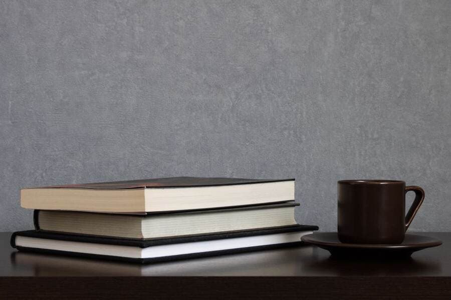 Livros empilhados ao lado de uma xícara sobre a mesa Livros empilhados ao lado de uma xícara sobre a mesa