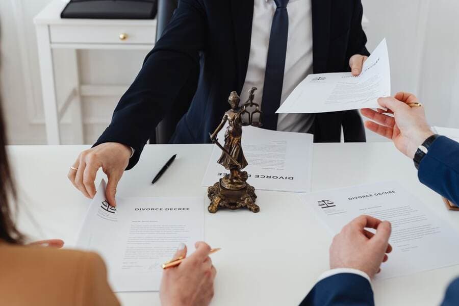 Advogado assinando documentos ao lado de uma estátua da justiça Advogado assinando documentos ao lado de uma estátua da justiça