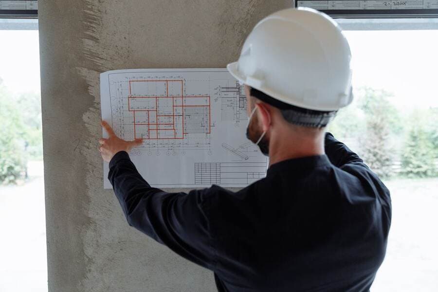 Engenheiro de capacete conferindo projetos em uma obra Engenheiro de capacete conferindo projetos em uma obra