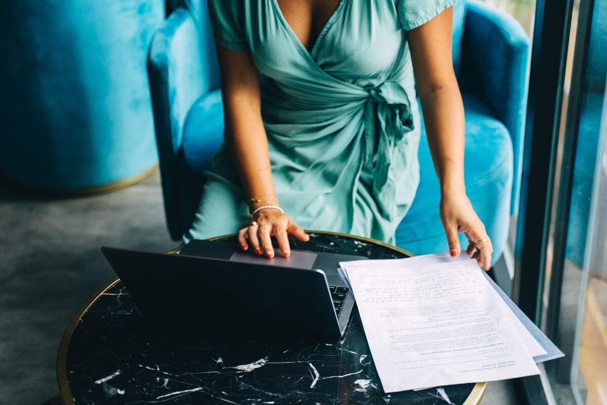 Onde encontrar clientes trabalhando de casa Mulher revisando documentos ao lado do notebook em casa