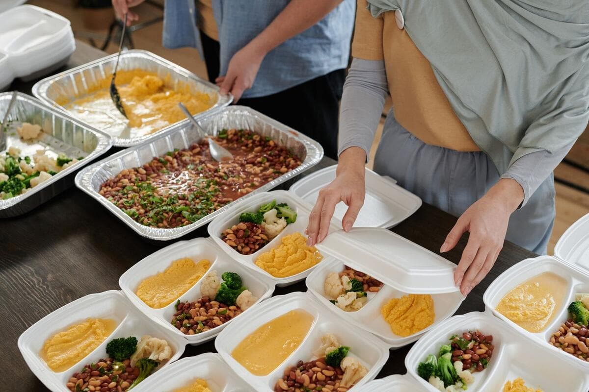 Venda por aplicativo de delivery e encomendas Pessoas montando marmitas em embalagens para entrega