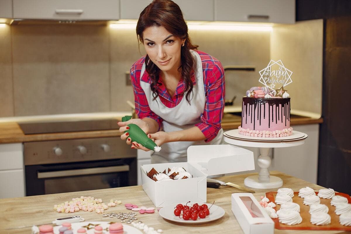 Confeiteira decorando um bolo em uma cozinha caseira