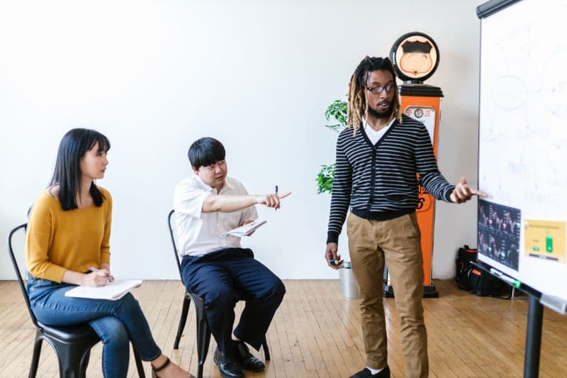 Nota fiscal para escolas, cursos livres e treinamentos A diverse group of adults in a learning session, actively engaging with a presentation.