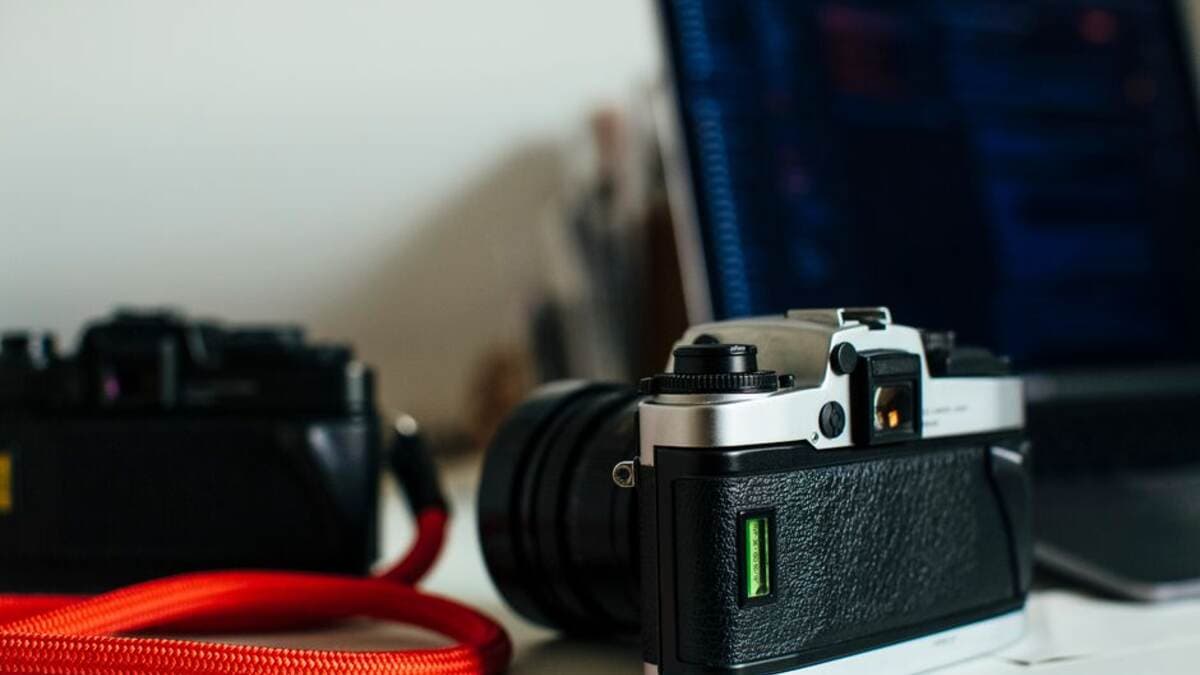 Câmera fotográfica ao lado do notebook de edição