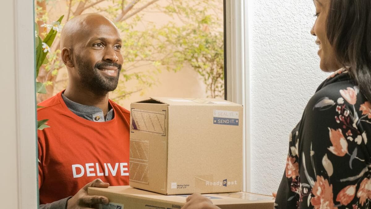 Qual nota emitir nas entregas Entregador entregando uma caixa a uma cliente sorridente na porta