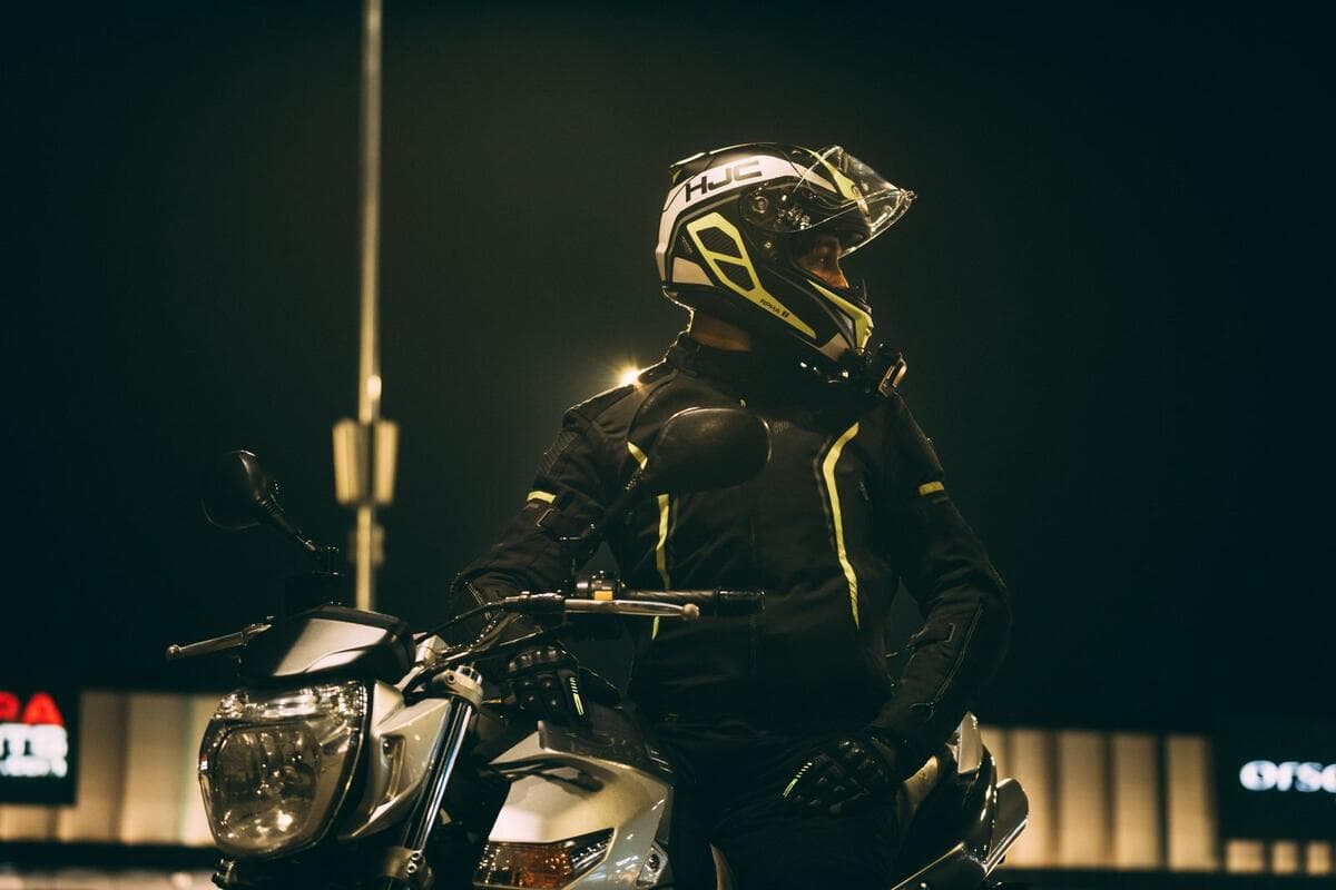 Aplicativos de entrega e clientes fixos Motociclista de capacete e roupa preta parado na rua à noite