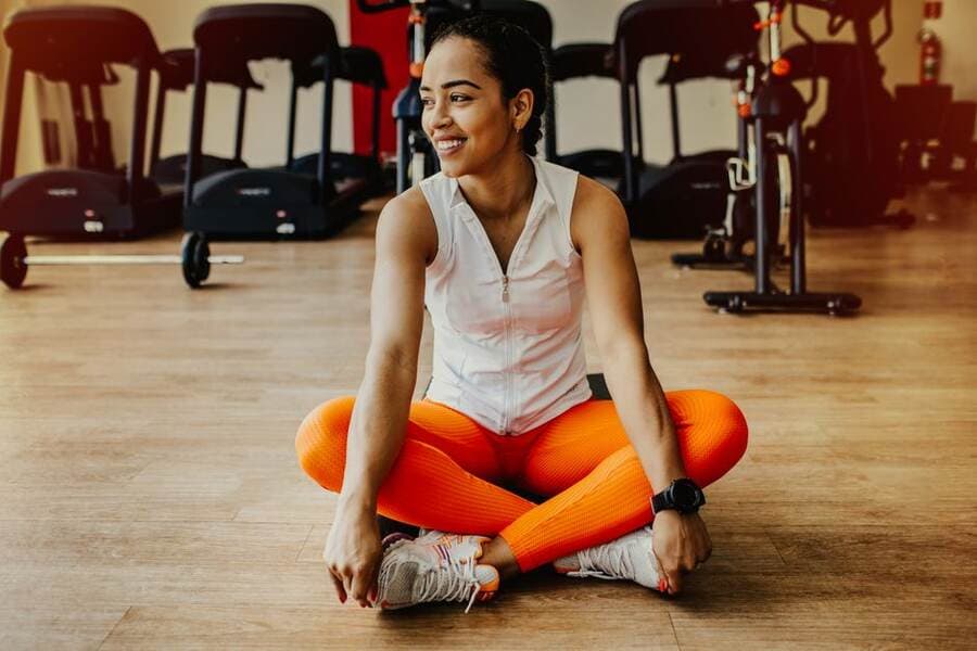 Mulher sorrindo sentada no chão de um estúdio de treino Mulher sorrindo sentada no chão de um estúdio de treino