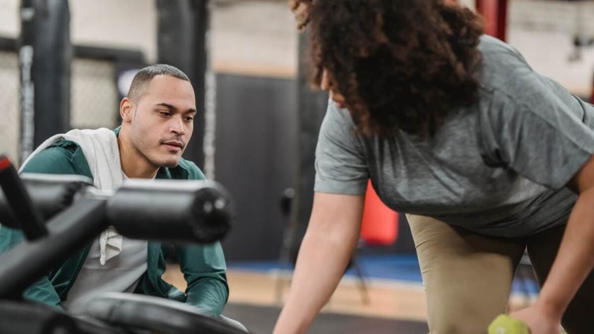 Personal trainer orientando um aluno durante o treino