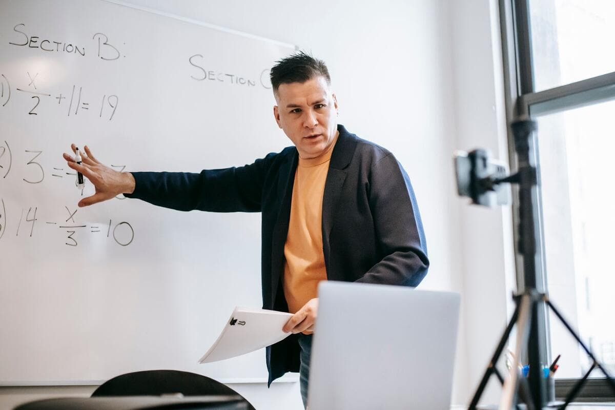 Aula particular pode ser MEI? Instrutor dando aula online de matemática diante do notebook e do quadro branco