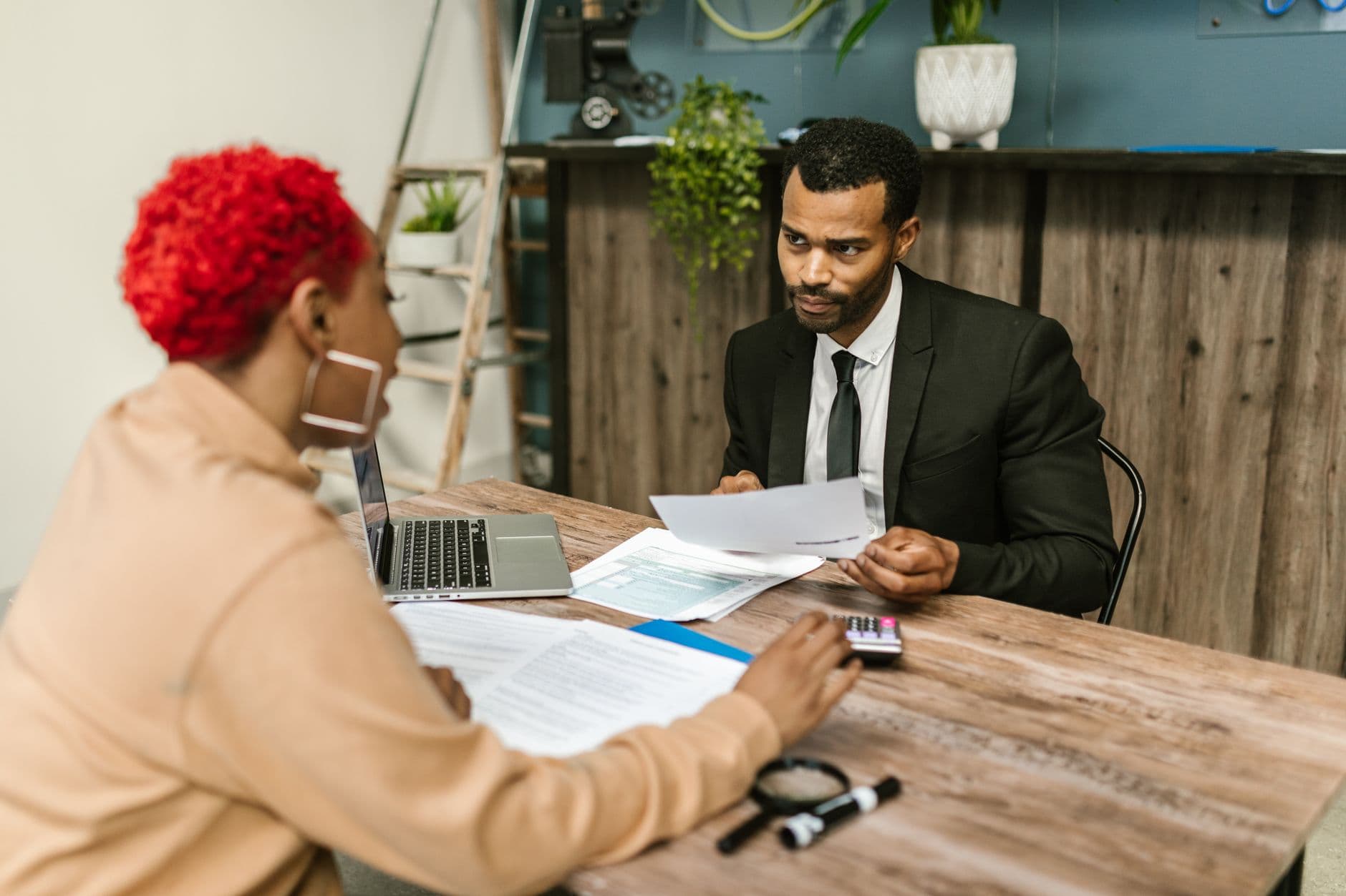 Quanto paga de imposto ao emitir nota como pessoa física A discussion between two professionals focusing on financial documents in a modern office setting.