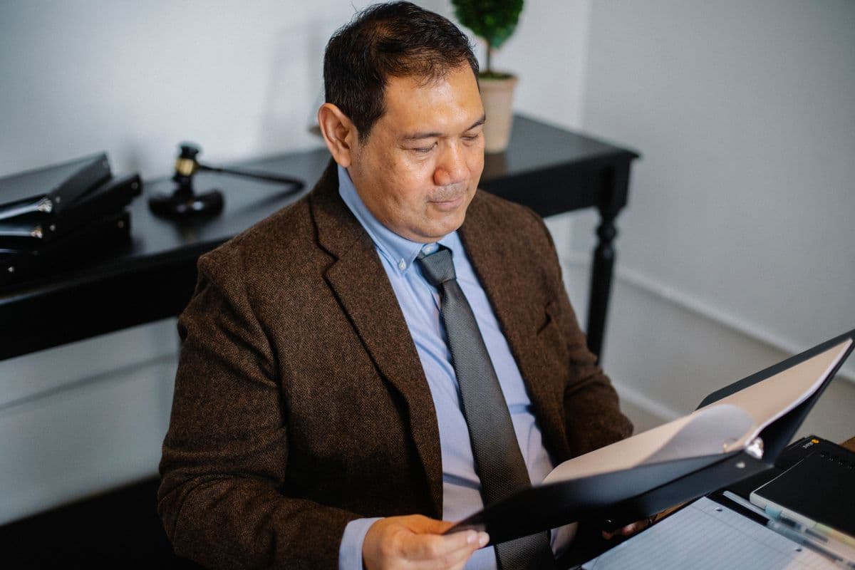 Empresária revisando documentos fiscais ao lado de um computador no escritório.