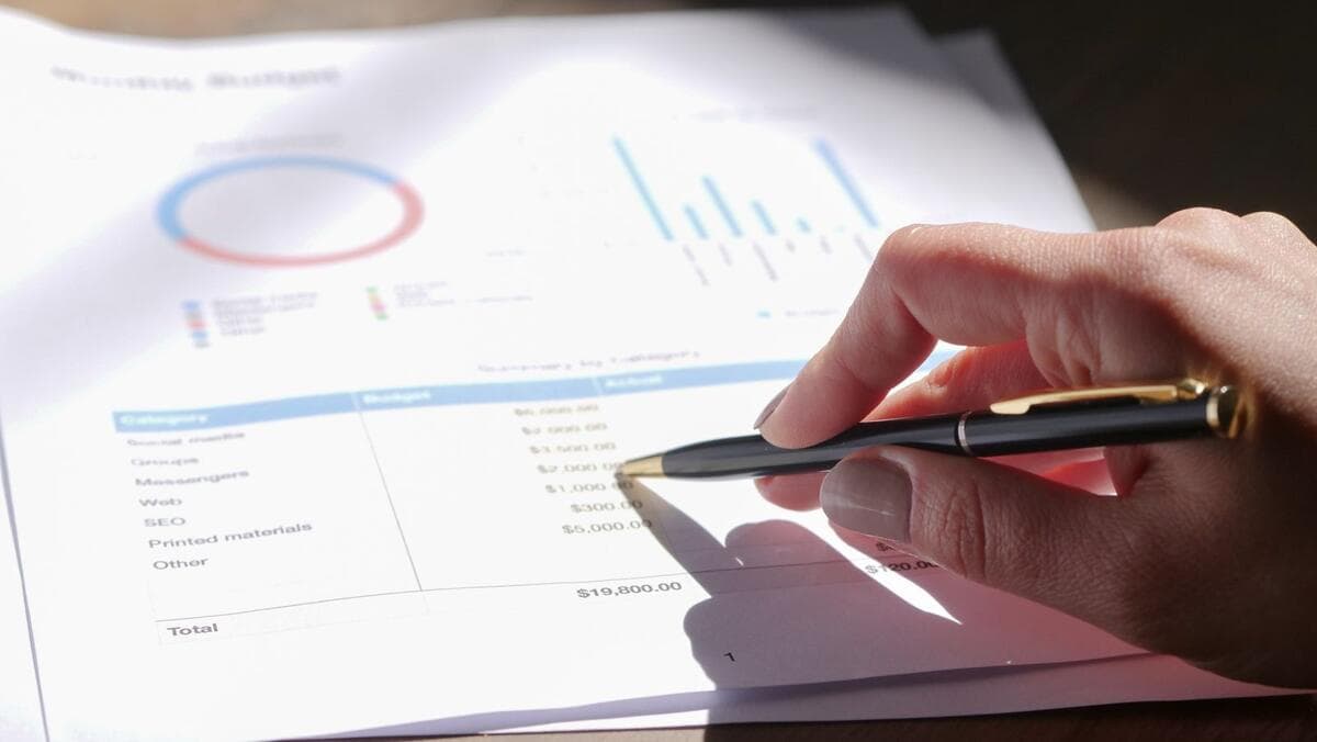 Opção 1: incluir as despesas no preço do serviço Mão com caneta analisando orçamento com gráficos em papel