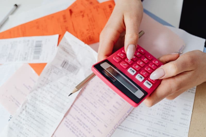 Nota rejeitada pela Sefaz: como ler o erro Hands using a pink calculator to manage expenses amidst various receipts and documents.