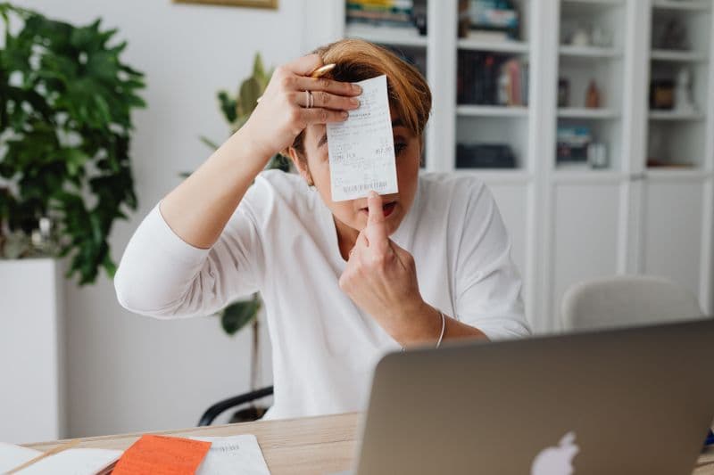 Relatório mensal de receitas do MEI: como preencher Businesswoman showing a receipt during a home office work session, highlighting technology integration.