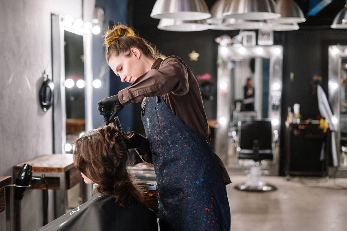 Cabeleireira aplicando coloração no cabelo de cliente em salão