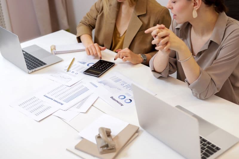 Simples Nacional: quando vale sair e migrar de regime Two professionals collaborating on financial documents in a modern office setting.